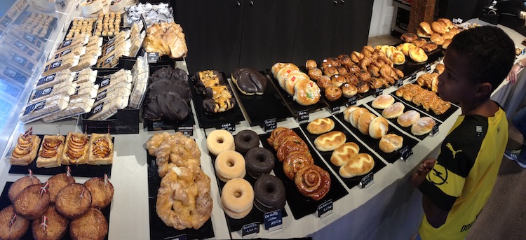 A huge array of cakes and pastries in a bakery in San Sebastián, Spain, and a little boy staring at them