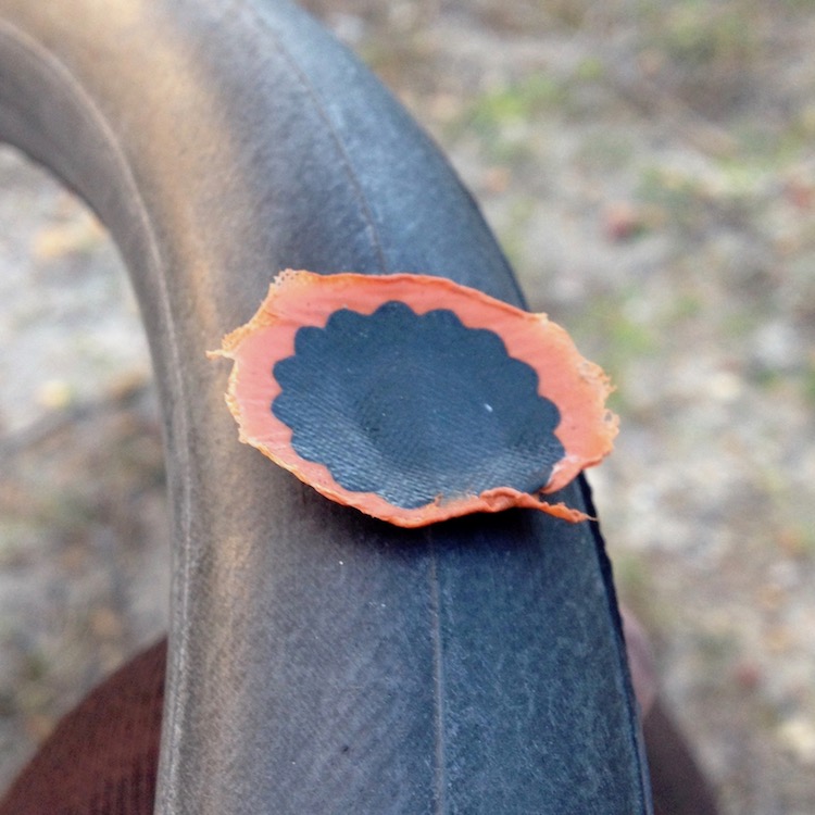 A partially inflated bicycle inner tube, with a puncture repair patch stuck on it in a very unprofessional manner.